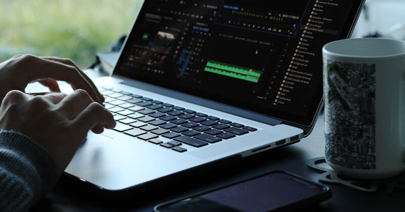 A video editor works on an audio waveform in Adobe Premiere Pro