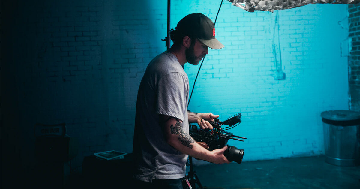 Mann mit Filmkamera in einem blauen Raum