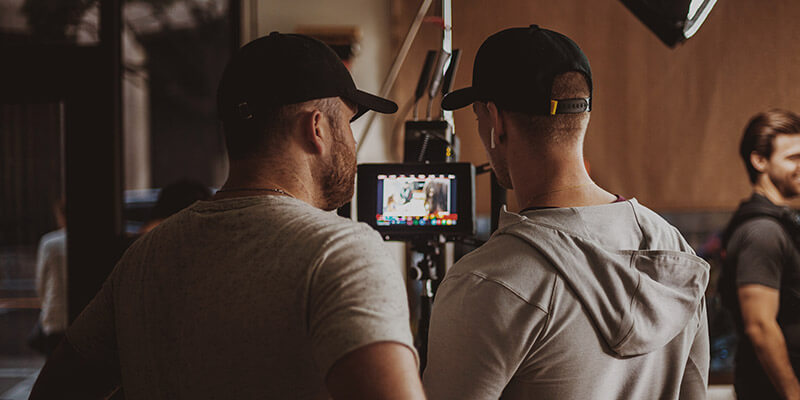 A digital imaging technician and a director of photography review footage on a small screen