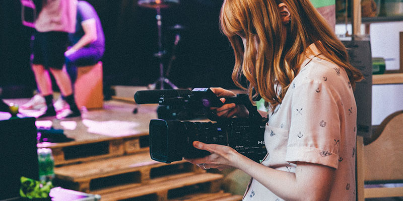 Een vrouw gebruikt een Panasonic filmcamera die ze huurde van een professionele videoproducent