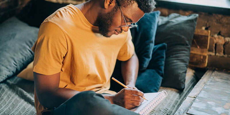 Freelancer schrijft creatieve ideeën op in zijn notitieboekje