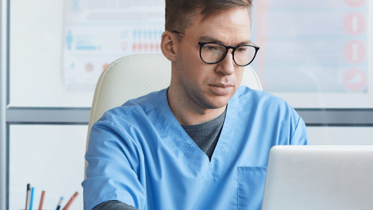 een mannelijke arts werkt op zijn laptop