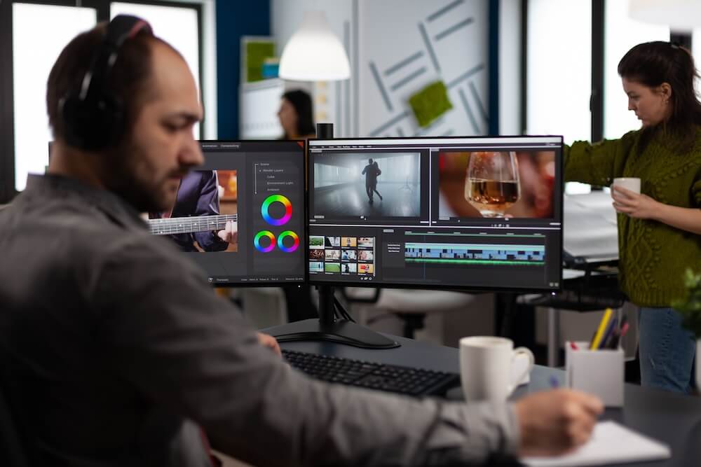 Video maker with headset working with footage and sound on pc with two displays Imagen de marcador de posición